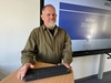 Mitarbeiter Uwe Schmidt steht an einem Pult, auf dem eine Tastatur liegt. Im Hintergrund ist auf einem Whiteboard das Wort "Abitur" zu lesen. 
